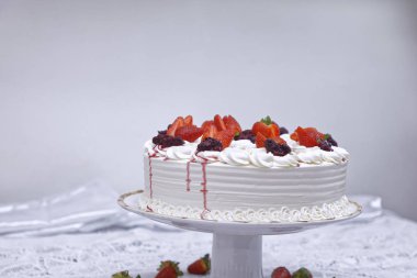 Krem şantili mascarpone keki ve beyaz tabakta çilek.