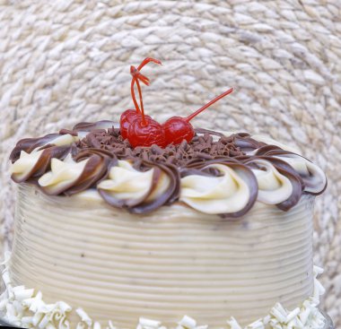 Tereyağlı kremalı pasta ve cam tabakta kirazlar.