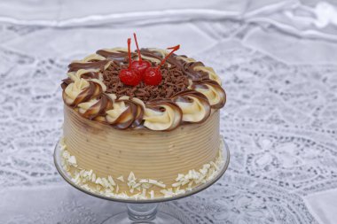 Tereyağlı krema, cam tabakta kirazla süslenmiş lezzetli pasta.