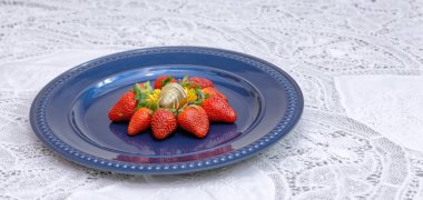 Bir sürü çilek ve mavi tabakta çikolata şekeri