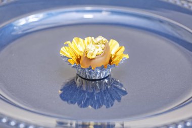 Sütlü çikolatalı şeker. Mavi tabakta altın fındıklı. 