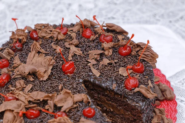 焼きたてのチョコレートケーキにココアパウダーのグレーズとチェリーを赤皿に飾り — ストック写真