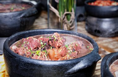 Siyah kil tabaklarda et ve sebze çorbasıyla birlikte et kebabını yakın.