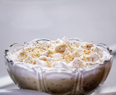 Beyaz arka planda cam tabakta kurabiye kırıntıları olan vanilyalı dondurma.