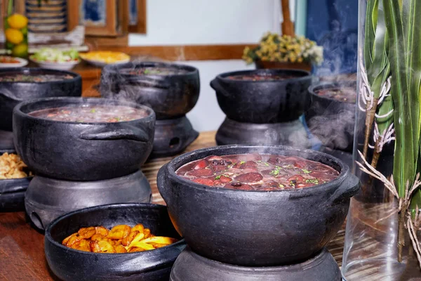 Lokanta arka planında ahşap masada ızgara sebzeli lezzetli rosto ile siyah killi yemekler. 