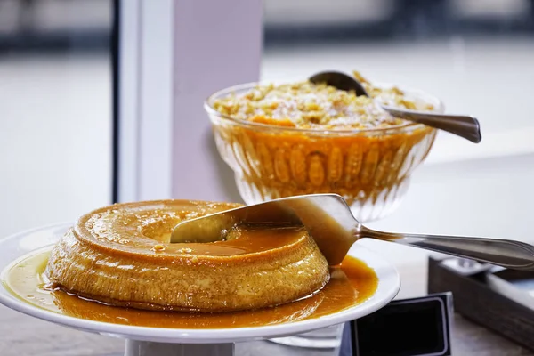 Ahşap masa arkasında vanilyalı dondurma ile karamel kremalı brulee.