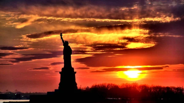A estátua da silhueta da liberdade no por do sol Fotografia De Stock