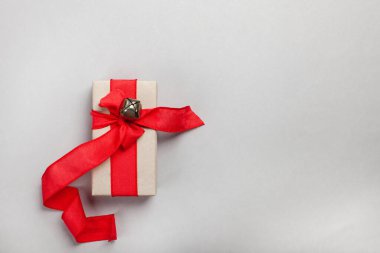 Gri arka planda kırmızı kurdeleli uzatılmış hediye kutusu.