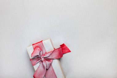 Gri arka planda kırmızı kurdeleli uzatılmış hediye kutusu.