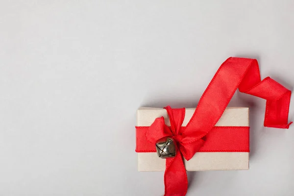 Långsträckt presentförpackning med ett rött band på en grå bakgrund Royaltyfria Stockfoton