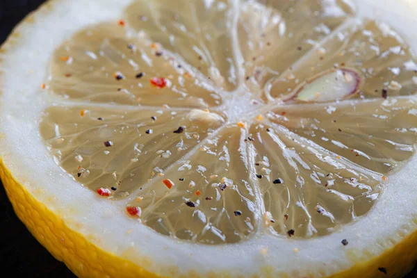 Uma fatia redonda de limão polvilhada com pimenta na mesa . — Fotografia de Stock