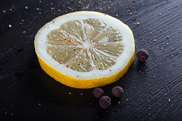 Uma fatia redonda de limão polvilhada com pimenta na mesa . — Fotografia de Stock