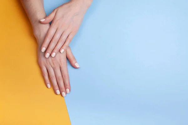 Piękne kobiece dłonie z klasycznym matowym manicure na niebiesko-żółtym tle — Zdjęcie stockowe