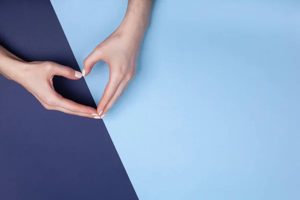 Les mains féminines montrent un symbole de coeur sur un fond bleu. Place pour le texte — Photo