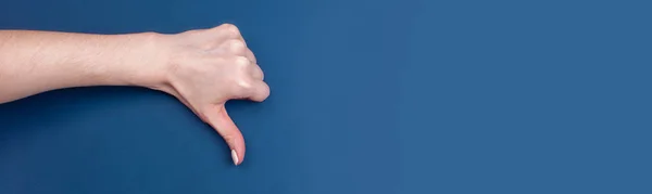 Kvinnlig hand visar tummen ner på blå bakgrund — Stockfoto