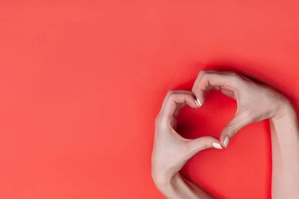 Les mains féminines montrent un symbole de coeur sur un fond rouge. Lieu pour le texte, espace de copie — Photo