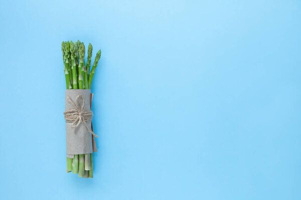 куча свежей зеленой спаржи на синем фоне
