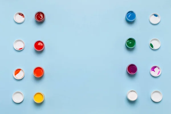 Dwa rzędy słoików z farbami gwasz na niebieskim tle — Zdjęcie stockowe