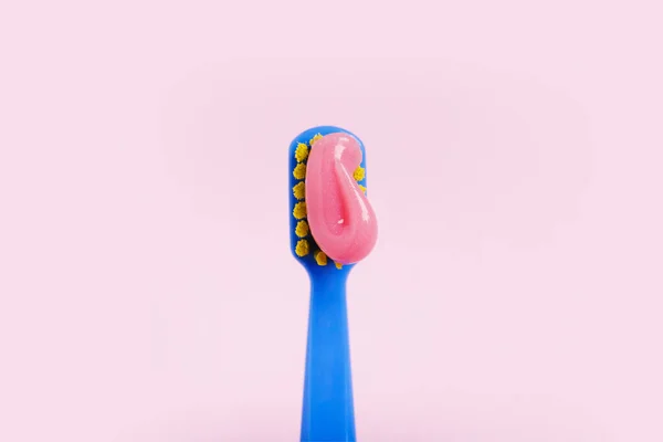 Cepillo de dientes brillante con pasta rosa de cerca sobre un fondo rosa — Foto de Stock