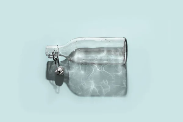 Koncepcyjna ilustracja braku wody. Pusta butelka rzuca długi cień, w którym widać wodę. — Zdjęcie stockowe
