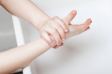 Çocuk ellerini ev banyosunda iyice yıkıyor.