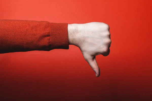 Το χέρι του ανθρώπου δείχνει τον αντίχειρα κάτω στο κόκκινο φόντο — Φωτογραφία Αρχείου