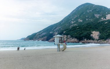 Shek O köyünün sahilinde koşan ve oynayan bir aile.