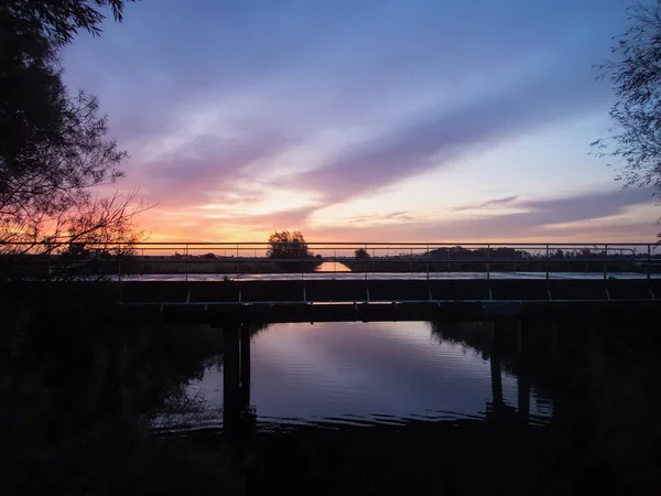 Blick auf einen bunten Sonnenaufgang auf einer Brücke an der Küste des Wattenmeeres — Stockfoto