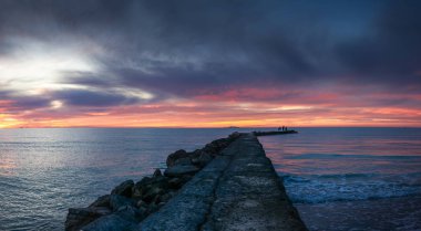 Gün batımında Toskana 'da Akdeniz' de bir iskelede siluetler.