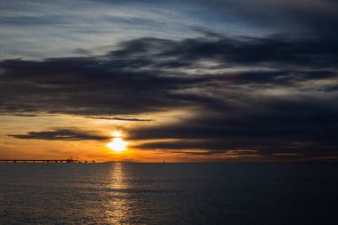 Günbatımında Toskana 'da Akdeniz' de bir rıhtım. Arka planda bir ada ve yelkenli var.
