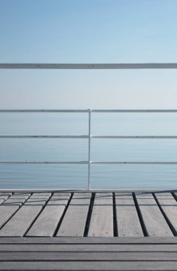 Basit beyaz çelik korkuluklar ve deniz kenarında ahşap zemin.