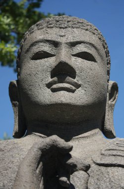 Güneşli bir günde gri bir Buda heykelinin başı.