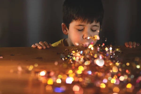 Genç bir çocuk Noel Parıltısı üflüyor.