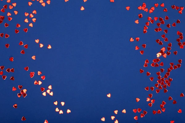 Mavi arka planda kırmızı parlak kalpler.