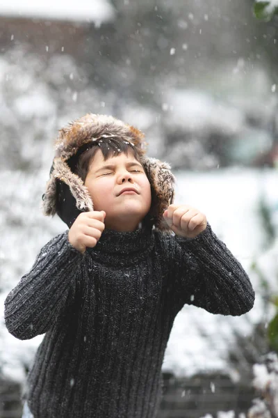 Genç çocuk şapkası diliyle kar yakalamaya çalışıyor..