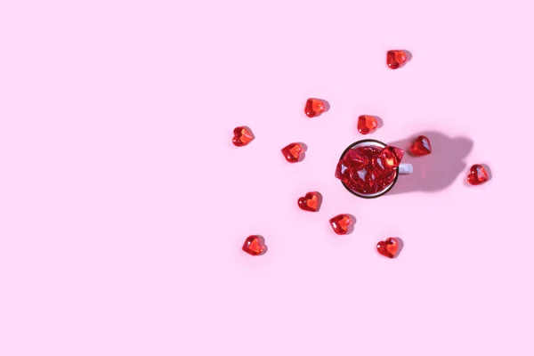 Una tazza rosa piena di cuori di vetro rosso . — Foto Stock