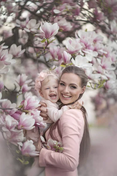 Bella e felice mamma con una figlia in fiore magnolia . — Foto Stock