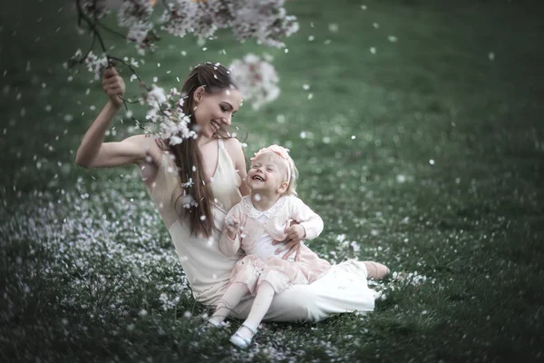 Máma a dcera v kvetoucí zahradě. — Stock fotografie