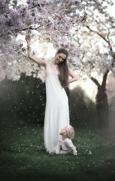 Mamá y su hija en un jardín con flores . — Foto de Stock