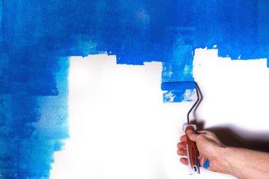 Mans el mavi boya ile beyaz bir duvar boyar.