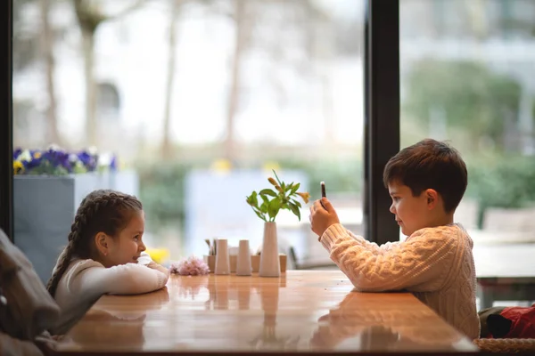 Bir oğlan akıllı telefonlu bir kızın fotoğrafını çekiyor..