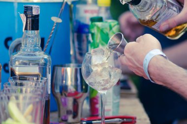 Barmenlerin elleri buzlu bardağa güçlü bir alkollü içecek doldurur.