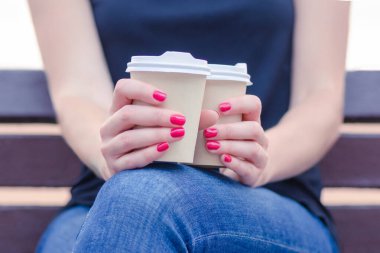 Sokaktaki kız bütün gün bankta oturuyor. Güneşli bir günde elinde fincanla güneşli bir bankta kot pantolonla