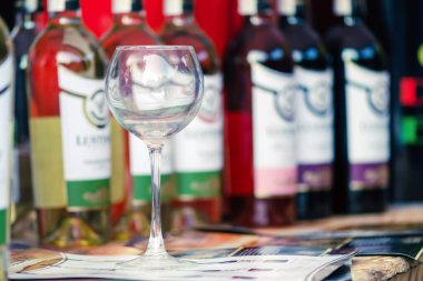 Sumy, Ukrayna - 25 Ağustos 2019. Sumy 'deki ikinci şarap festivali. Kırmızı ve beyaz şarap şişelerinin arasında boş bir şarap kadehi duruyor. Şarap tatma.