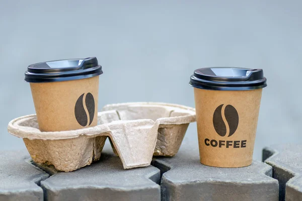 two take-away cups of coffee. one cup in the holder. coffee to go