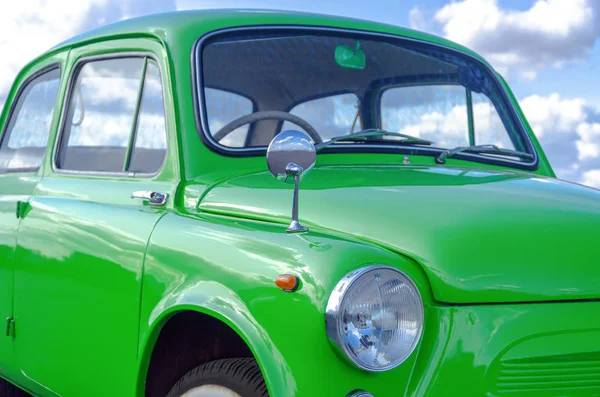 Oldtimer im Retro-Look. Kleines sowjetisches Retro-Auto grüner Farbe gegen den wolkenverhangenen Himmel. Seitenansicht Scheinwerfer — Stockfoto