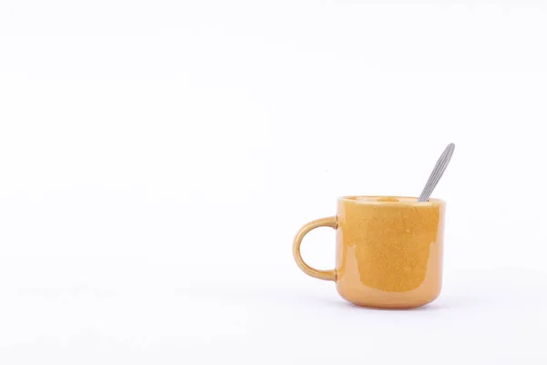 Kahverengi kahve, çay ya da sütlü bardak ve beyaz arka planda kaşık izole edilmiş içecek.
