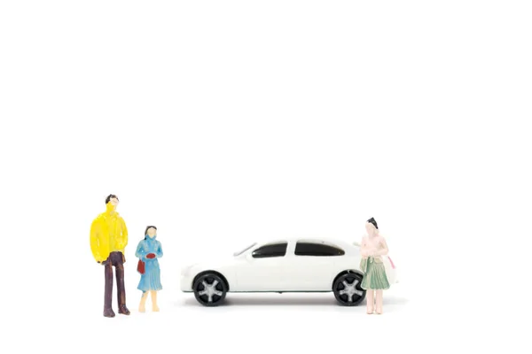 Miniature figures of people and car on white background