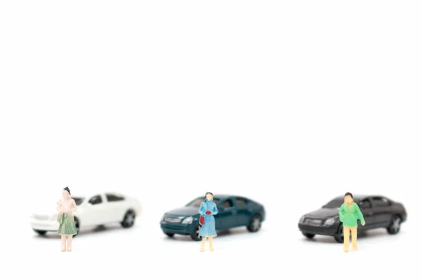 Miniature figures of women and car on white background