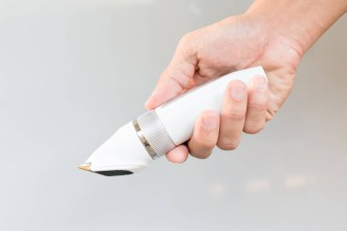 Saç kesme makineleri gri arka plan üzerinde tutan el 